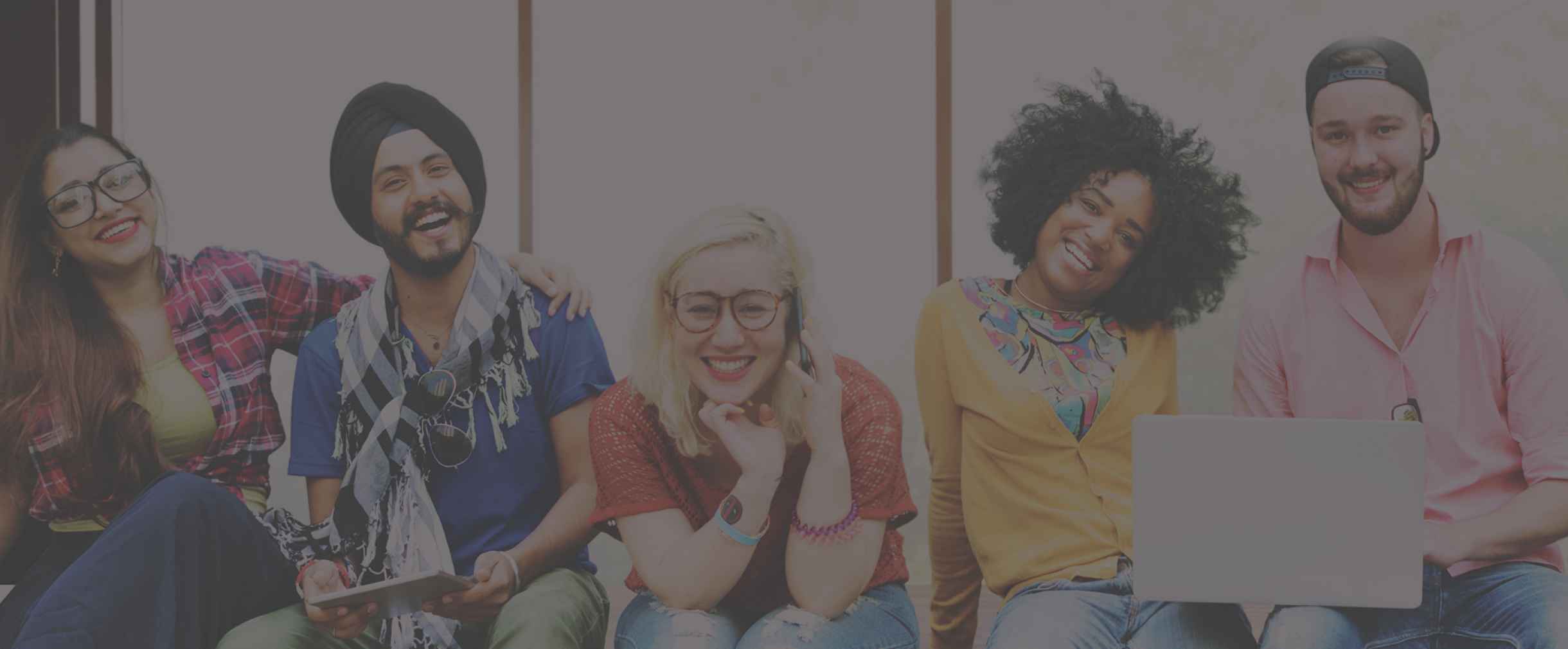 Group of 5 young adults sitting side by side smiling